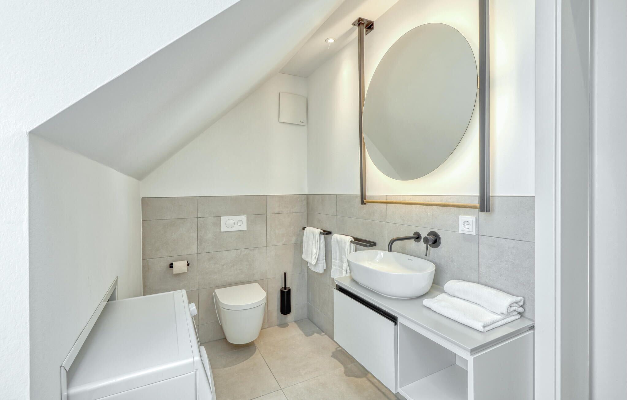A modern bathroom with a toilet, sink, and mirror.