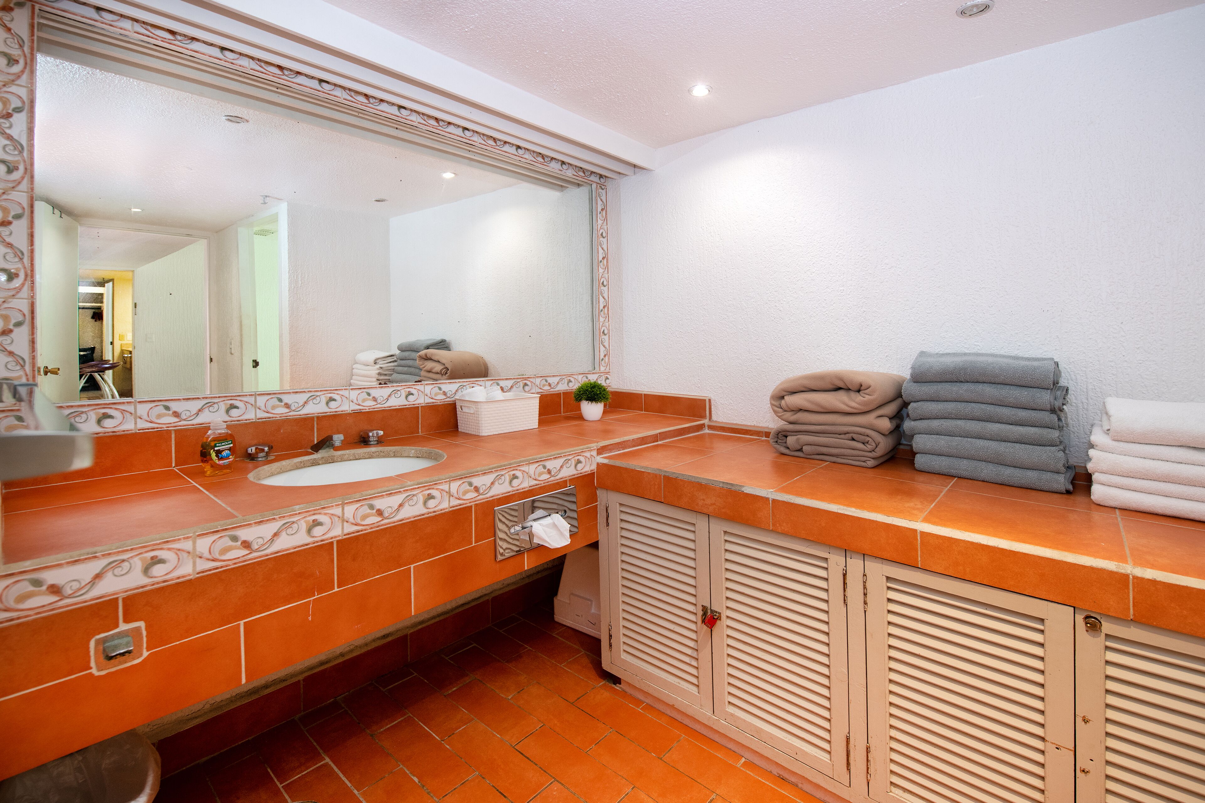 A bathroom with a large mirror, two sinks, a towel rack, and a cabinet.