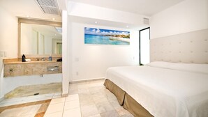 A bedroom with a large bed, a bathroom with a mirror, and a painting of a beach scene.