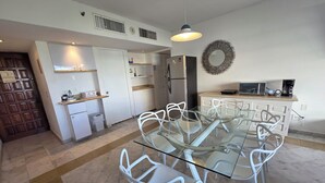 A modern kitchen with white cabinetry, a glass dining table, and white chairs.
