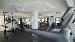Une salle de sport équipée de matériel d’exercice, d’un tapis de course et d’un banc de musculation.
