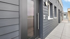 Ein modernes Gebäude mit einer dunkelgrauen Fassade, einer Metalldür und einem kleinen Fenster mit der Nummer 243.