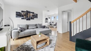 Ein modernes Wohnzimmer mit grauem Sofa, Holztisch und einer Weltkarte als Wandbild.