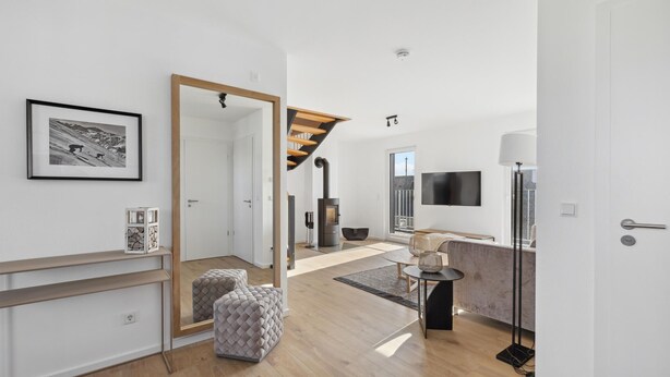 A modern living room with a wooden floor, a fireplace, a TV, and a large mirror. - Awesome apartment in Winterberg with sauna (Winterberg)
