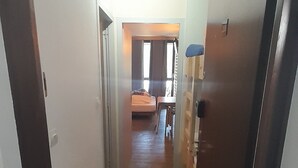 Un corridoio che porta a una camera da letto con un letto, una scrivania e una sedia.