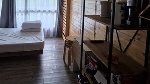 Una stanza con un letto, letti a castello in legno, un tavolino e una finestra con tende.