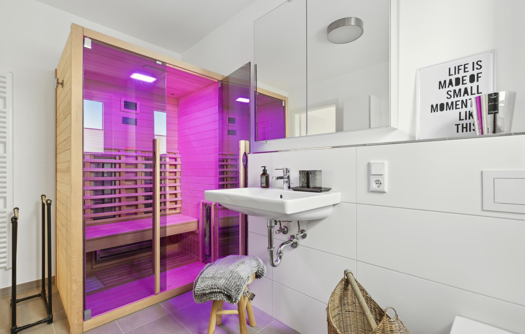 Un baño moderno con cabina de ducha de vidrio, un lavabo blanco y una frase motivacional en la pared.