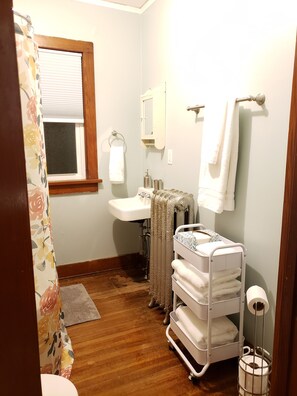A bathroom with a wooden floor, a white sink, a mirror, a towel rack, and a white towel rack. - Historic Rectory Retreat in Stockbridge – Getaway for 8-12 Guests (Stockbridge)