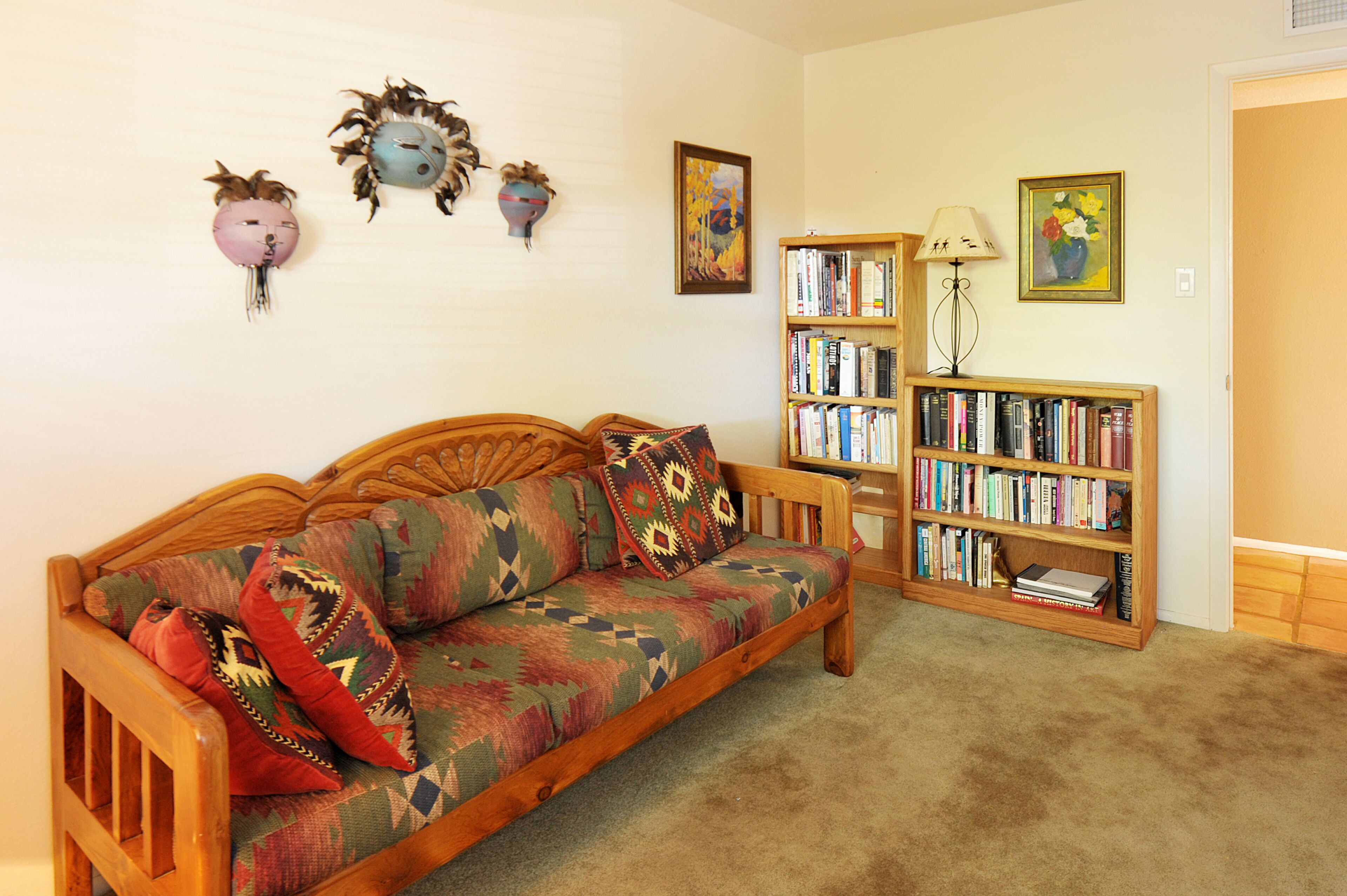 Un salón acogedor con un sofá de madera, una estantería y decoración en las paredes.