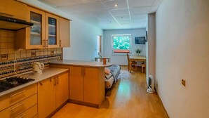 Una cocina compacta con armarios de madera, salpicadero de azulejos y un pequeño comedor con mesa y sillas.