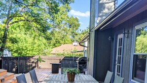 A wooden deck with a table and chairs, surrounded by a fence and trees. - South Austin Charmer with Backyard Oasis (Austin)