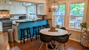 A modern kitchen with white cabinets, a blue island, and black bar stools. - South Austin Charmer with Backyard Oasis (Austin)