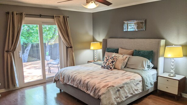 A bedroom with a bed, two bedside tables, a ceiling fan, and a window with curtains. - South Austin Charmer with Backyard Oasis (Austin)