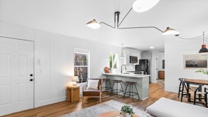 A modern kitchen with white cabinets, a central island, and bar stools. - Modern Cabin (Alder) (Dunsmuir)