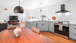 A modern kitchen with grey cabinets, a wooden dining table, and a built-in oven. - Modern Cabin (Blue Spruce) (Dunsmuir)