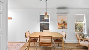 Een eethoek met een houten tafel en stoelen, een hanglamp en een schilderij aan de muur.