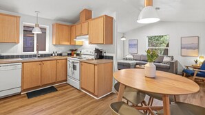 Una cucina moderna con mobili in legno, un piano cottura e un'area pranzo con un tavolo rotondo e sedie.