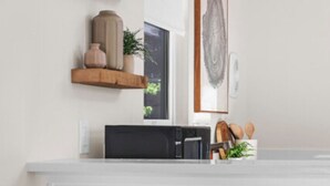 A modern kitchen with white cabinetry, a microwave, and two stools. - Tiny Home  - (Cedar) (Dunsmuir)