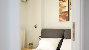 Une chambre à coucher comprenant un lit, une table de chevet, un climatiseur fixé au mur et un tableau.