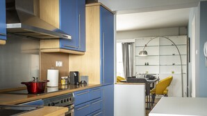 Une cuisine moderne avec des meubles bleus, une casserole rouge et un îlot central blanc.