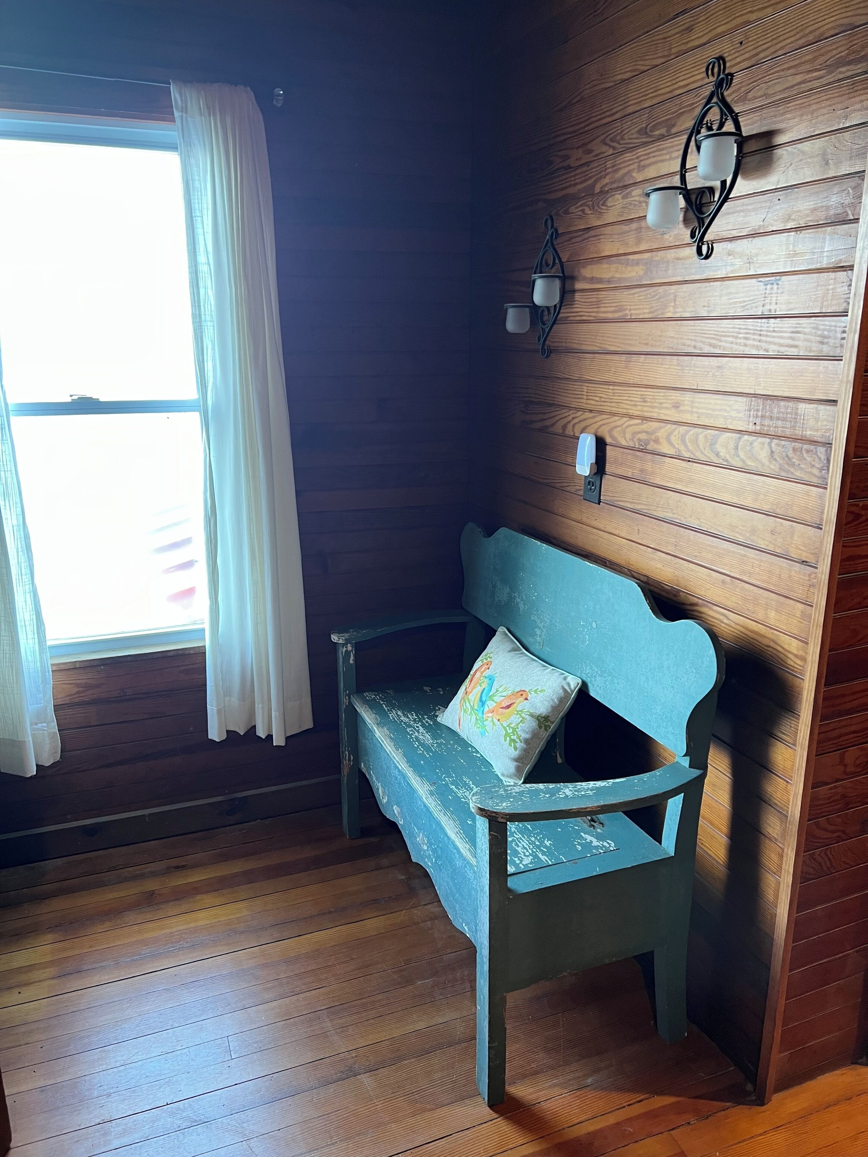 Una stanza con rivestimento in legno, una panca e un lampadario a parete.