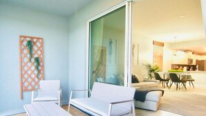 A modern outdoor seating area with a white sofa and chairs, a small table, and a decorative lattice wall.