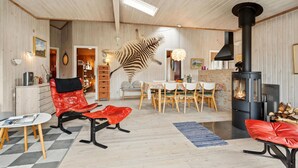 Un salon chaleureux, agrémenté d’un grand squelette d’animal en guise de décoration, d’une cheminée et d’un coin repas avec des meubles en bois.