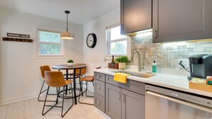 Una cocina moderna con armarios grises, lavavajillas y un comedor con dos sillas y una mesa.
