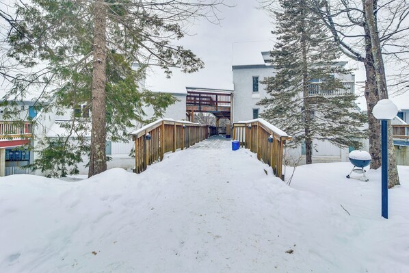 A snow-covered pathway leading to a building with a wooden bridge. - Golf, Hike & Swim: Gem < 1 Mi to Sugarbush Resort (Warren)