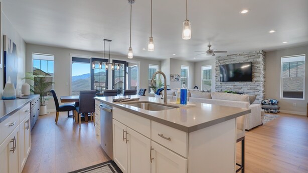 A spacious kitchen with a central island, dining area, and a living room with a stone fireplace.