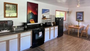 Une cuisine équipée d’une cuisinière, d’un évier et d’un réfrigérateur. On y trouve des placards en bois et une table à manger avec des chaises.