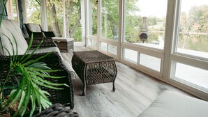 A covered patio with wicker furniture and a view of a lake. - Beautiful, Peaceful Lakefront home in ❤️ of Bourbon Country in Shelbyville, KY (Shelbyville)