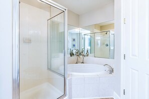 Een bad/douchecombinatie, een bubbelbad, een haardroger, handdoeken