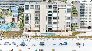 Un hotel frente a la playa con varios pisos, piscina y acceso directo a la orilla.
