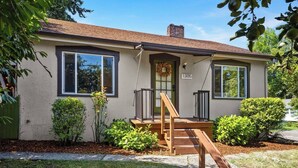 A single-story house with a front porch, a green door, and a mailbox marked with the number 1305. - Charming 1920s Olympia home with game room, fenced yard, blocks from Capitol (Olympia)