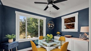 A modern kitchen with a glass dining table, yellow chairs, and a ceiling fan. - Charming 1920s Olympia home with game room, fenced yard, blocks from Capitol (Olympia)