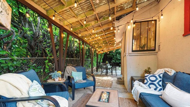 An outdoor patio area with wicker furniture, string lights, and a fire feature. - Charming 1920s Olympia home with game room, fenced yard, blocks from Capitol (Olympia)
