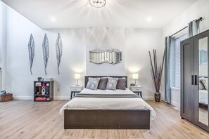 A modern bedroom with a large bed, a bookshelf, decorative wall art, and a wardrobe. - Hidden Gem | JZ Vacation Rentals (St. Louis)