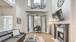 A spacious living room with a sofa, a coffee table, a fireplace, and a desk with a chair. - Hidden Gem | JZ Vacation Rentals (St. Louis)