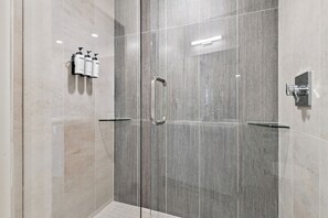 Une cabine de douche moderne dotée d’une porte en verre, d’une poignée métallique et d’un robinet fixé au mur.