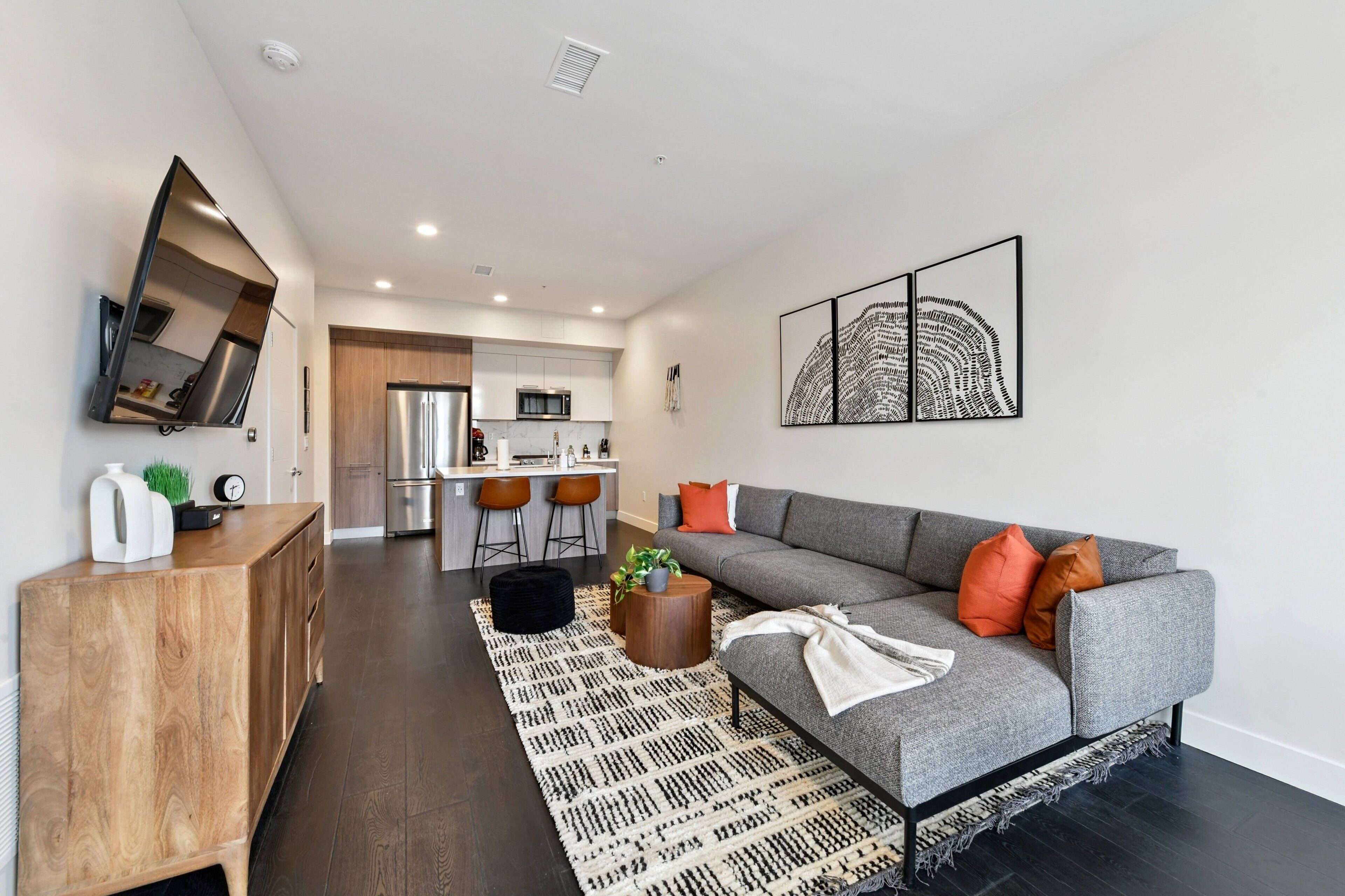 Un salon moderne avec un canapé gris, un meuble en bois et un téléviseur à écran plat.