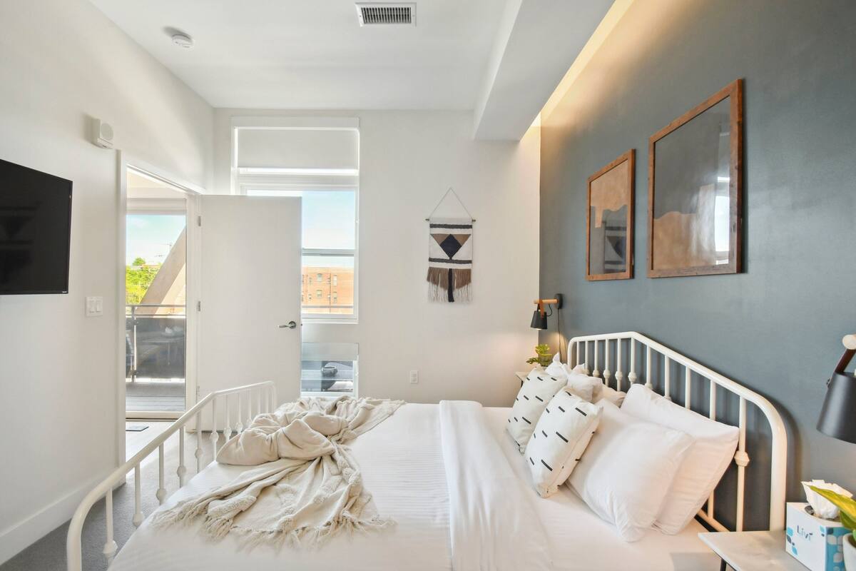 Une chambre à coucher comprenant un lit, une télévision, une fenêtre et une porte donnant sur un balcon.