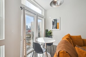 A modern living room with a white round table, black chairs, and a mustard-colored sofa. - Espadin Condos I (Denver)