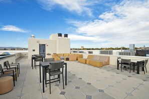A rooftop terrace with outdoor seating, including tables and chairs, and a small bar area. - Espadin Condos I (Denver)