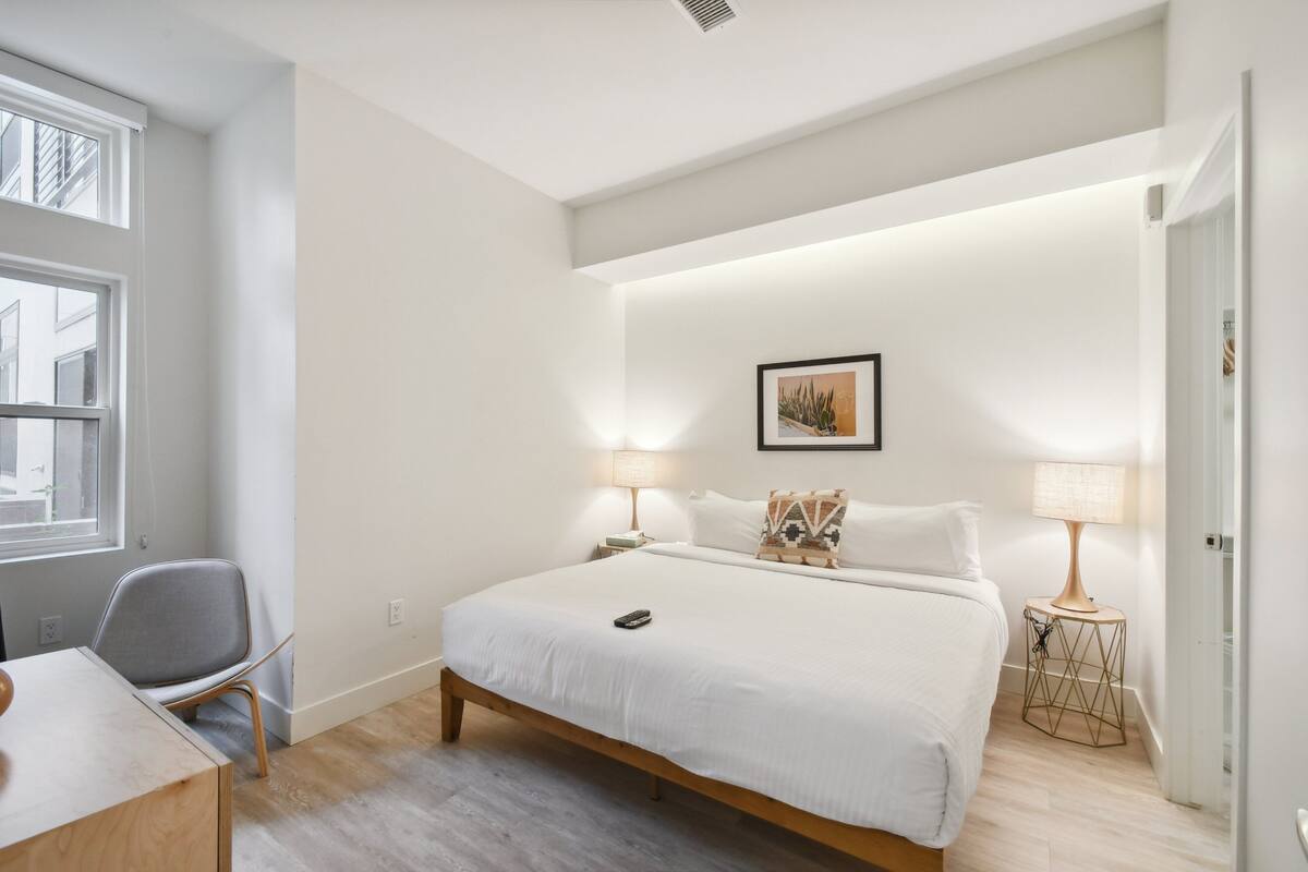 Une chambre moderne avec un grand lit, deux lampes de chevet, une chaise et une petite table.