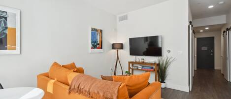 A modern living room with a sofa, a TV, and a lamp.