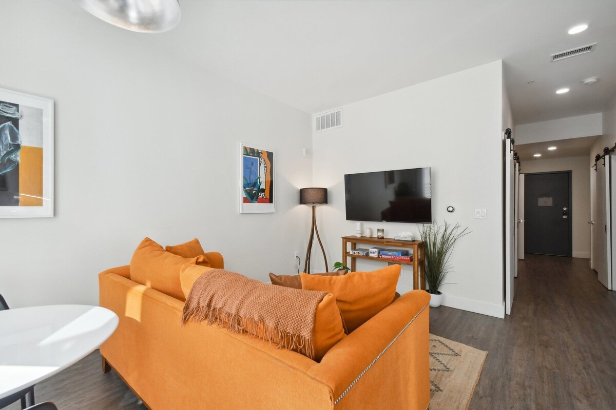 A modern living room with a sofa, a TV, and a lamp.