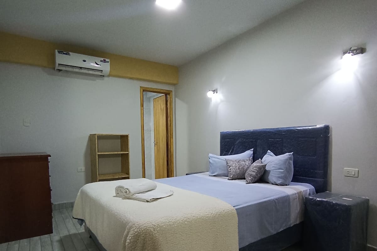 Une chambre d’hôtel équipée d’un lit, d’une table de chevet et d’un appareil de climatisation fixé au mur.