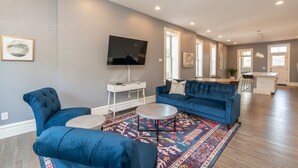 A modern living room with a blue sofa, a TV, and a patterned rug. - Parkside Comfort | JZ Vacation Rentals (St. Louis)