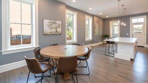 A spacious kitchen with a central island, large windows, and a dining area with a round table and chairs. - Parkside Comfort | JZ Vacation Rentals (St. Louis)